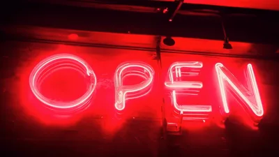 Red Neon Open Sign Flickering On A Dark Wall