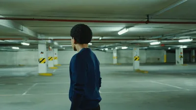 Young Man Looking Around An Empty Underground Parking Garage