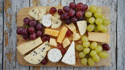 Assorted Cheese And Grape Platter On Wooden Board