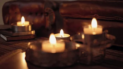 Three Lit Candles Flickering On A Dark Wooden Table