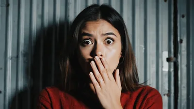 Young Woman Looking Shocked With Hand Over Mouth