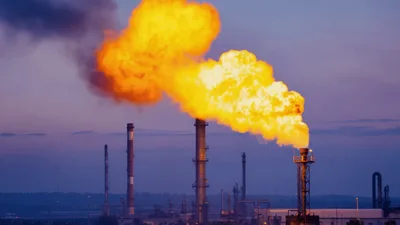 Industrial Flare Stack Burning Natural Gas At Sunset