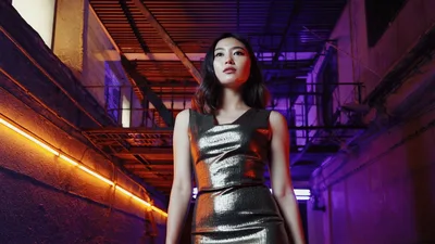 Young Asian Woman Walking Through Neon Lit Alleyway