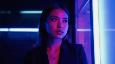 Young Asian Woman Standing Under Changing Neon Lights