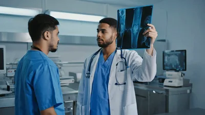 Two Doctors Discussing Knee X-Ray Results In Hospital