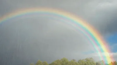 Vibrant Double Rainbow Arcing Over Green Forest Trees