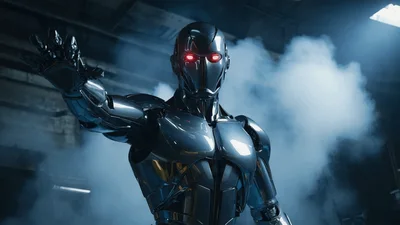 Metallic Humanoid Robot Standing In A Smoky Industrial Warehouse