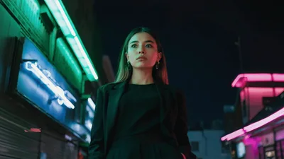 Young Woman Walking Through Neon Lit City Street