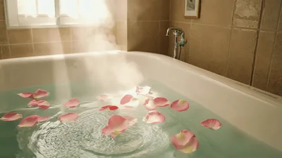Steaming Bathtub Filled With Water And Rose Petals