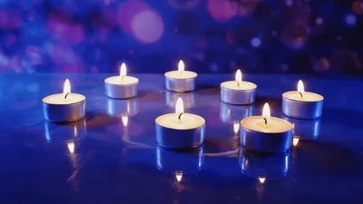 Seven Burning Tea Light Candles On Reflective Surface