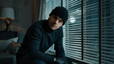 Man In Beanie And Gloves Looking Out Window