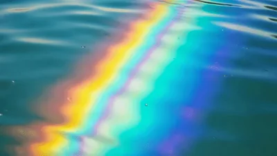 Oil Slick Creating Rainbow Patterns On Calm Ocean Water
