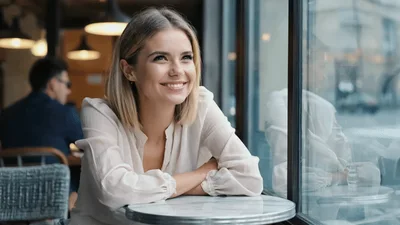 Smiling Young Woman Sitting At A Cafe Window