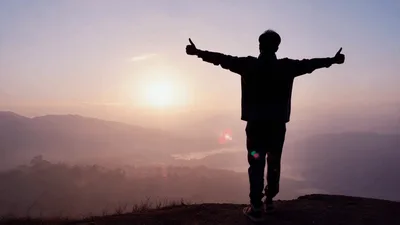 Man Standing On Mountain Peak At Sunrise