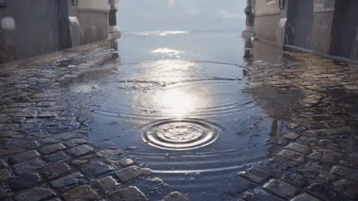Raindrops Creating Ripples In A Cobblestone Street Puddle