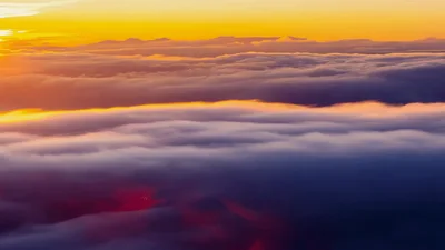 Aerial View Of Golden Sunset Clouds Moving Over Mountains