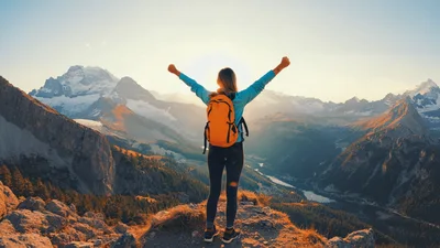 Hiker Standing With Arms Raised On Mountain Peak