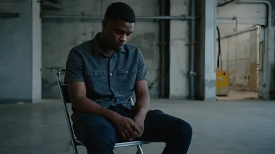 Young Man Sitting Alone In An Empty Warehouse