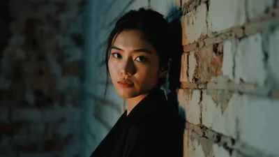 Young Asian Woman Leaning Against A Brick Wall