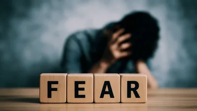 Wooden Blocks Spelling Fear With Distressed Person In Background