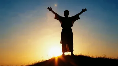 Silhouette Of A Person Standing With Arms Raised Outdoors
