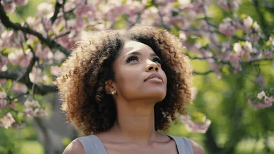 Young Woman Enjoying Springtime Under Blooming Cherry Blossom Tree