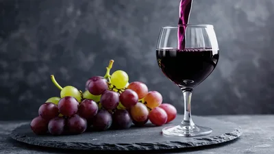 Red Wine Pouring Into A Glass With Grapes