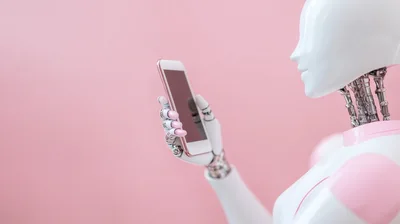 Humanoid Robot Holding A Smartphone Against Pink Background
