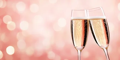 Two Champagne Flutes Toasting Against A Pink Bokeh Background