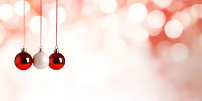 Three Christmas Ornaments Hanging Against Blurred Red Background