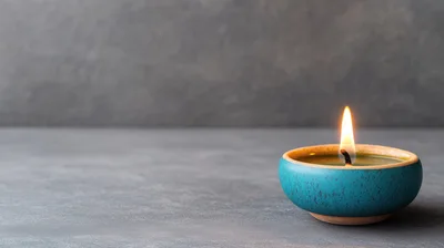 Lit Teal Ceramic Candle On Grey Surface