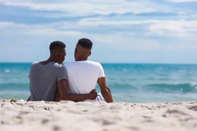 Two Men Sitting Together On A Beach