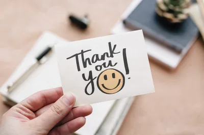 Hand Holding A Thank You Note With A Smiley Face