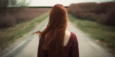 Woman With Long Red Hair Walking Down Country Road