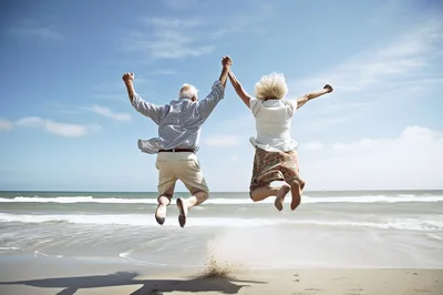 Senior Couple Jumping For Joy On The Beach