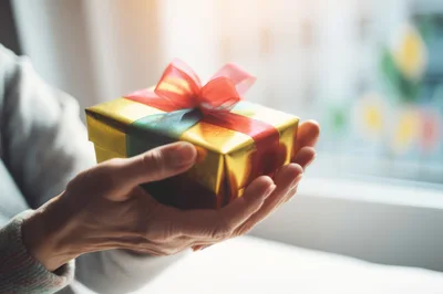 Person Holding A Golden Gift Box
