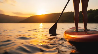 Person Paddleboarding On A Lake At Sunset