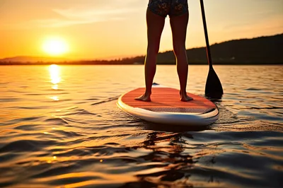 Woman Paddleboarding On A Lake At Sunset