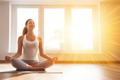 Young Woman Meditating In Lotus Position At Home