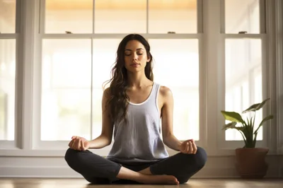 Young Woman Meditating In Lotus Position At Home
