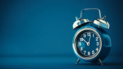 Blue Alarm Clock On Solid Blue Background