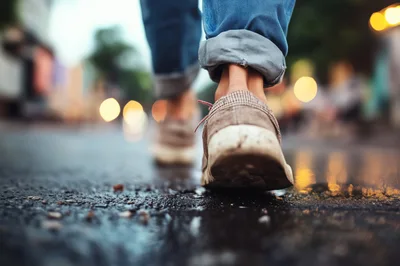 Person Walking In Casual Shoes On Wet City Street
