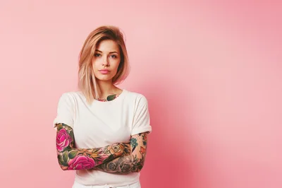Young Woman With Tattoos Posing Against Pink Background