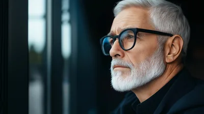 Thoughtful Elderly Man Looking Out A Window