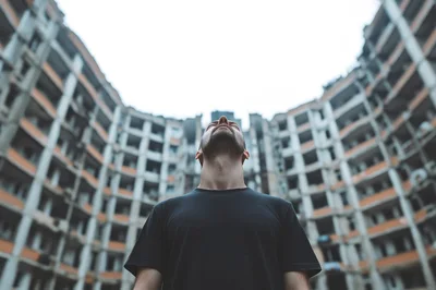 Man Standing Before A Destroyed Residential Apartment Building