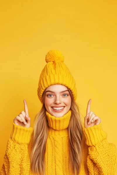Young Woman In Yellow Winter Clothing Pointing Upwards