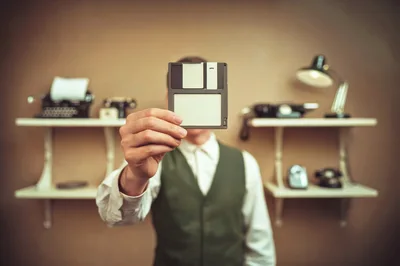 Man Holding Vintage Floppy Disk Over Face