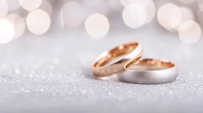 Two Wedding Rings Resting On A Glittering Surface