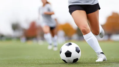 Female Soccer Player Dribbling Ball on Field