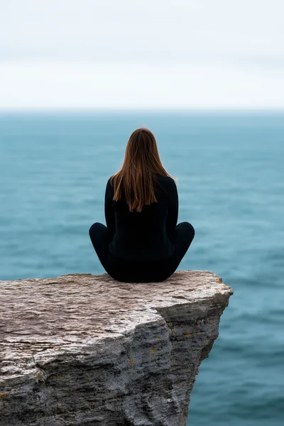 Woman Meditating In Lotus Position On A Sea Cliff